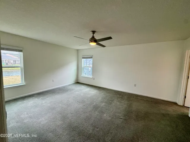 an empty room with windows and chandelier fan