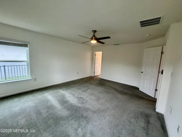 an empty room with chandelier fan and windows