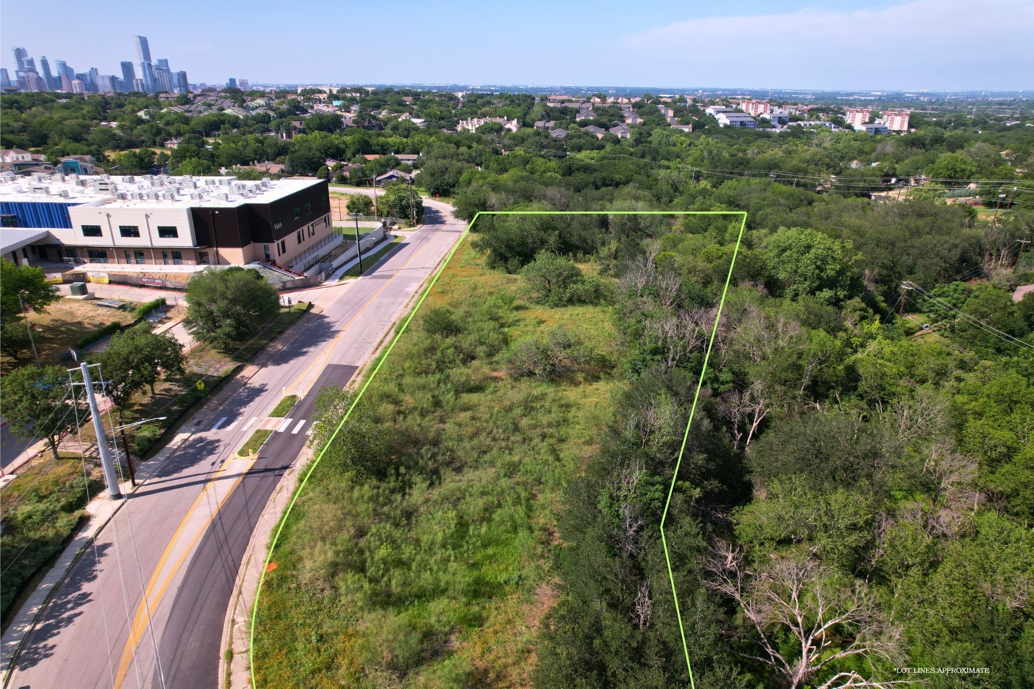 2813-2827 Metcalfe Road Austin, TX 78741 - Photo 2 of 13 A prime lot opportunity with established trees, set against a backdrop of urban development in South Austin