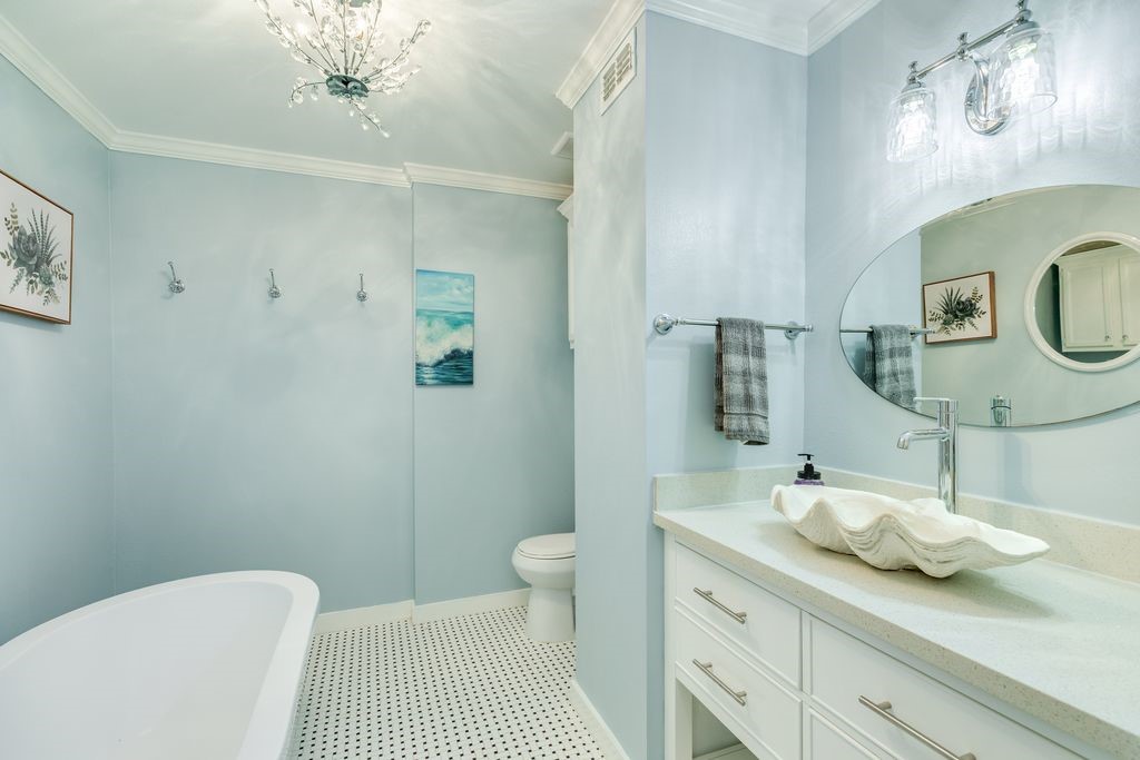 7516 Stewart Road Galveston, TX 77551 - Photo 22 of 25 a bathroom with a granite countertop sink a toilet and a mirror