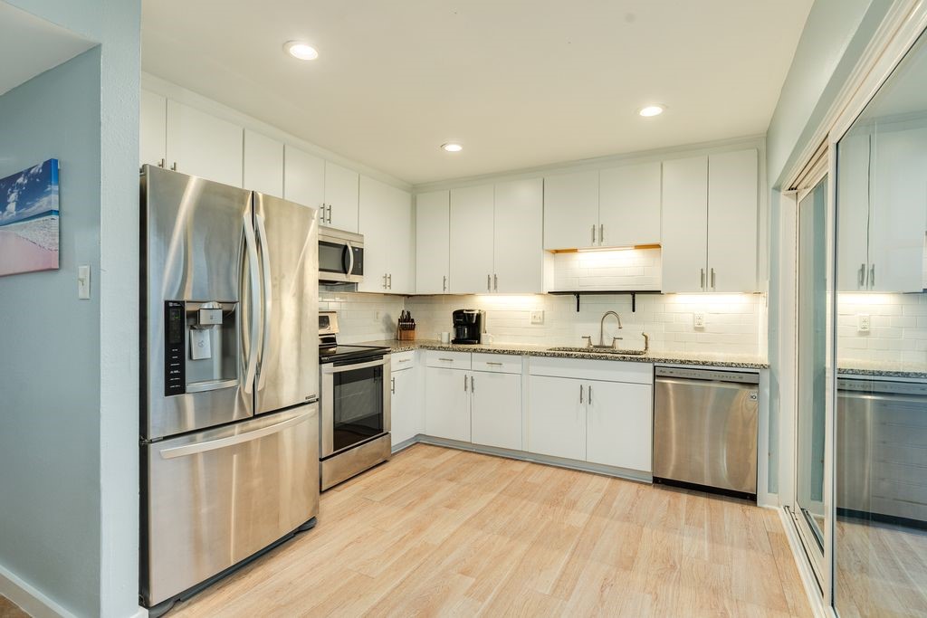 7516 Stewart Road Galveston, TX 77551 - Photo 9 of 25 a kitchen with granite countertop stainless steel appliances and refrigerator