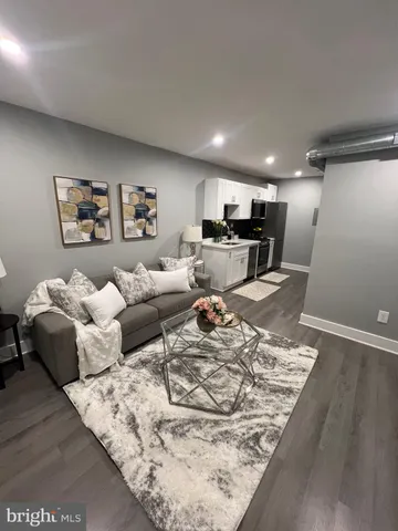 a living room with couches and kitchen view with wooden floor