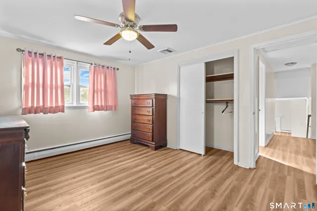an empty room with wooden floor closet and windows