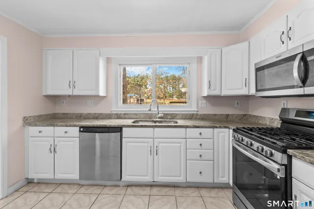 a kitchen with granite countertop white cabinets white stainless steel appliances and a sink