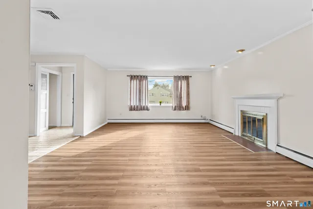 a view of an empty room with a window and wooden floor
