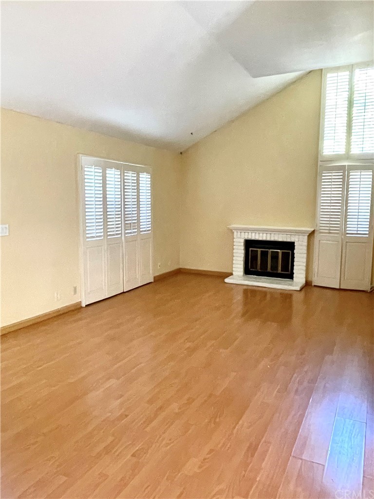48 Riverstone, Unit 60 Irvine, CA 92606 - Photo 5 of 31 an empty room with a fireplace and wooden floor