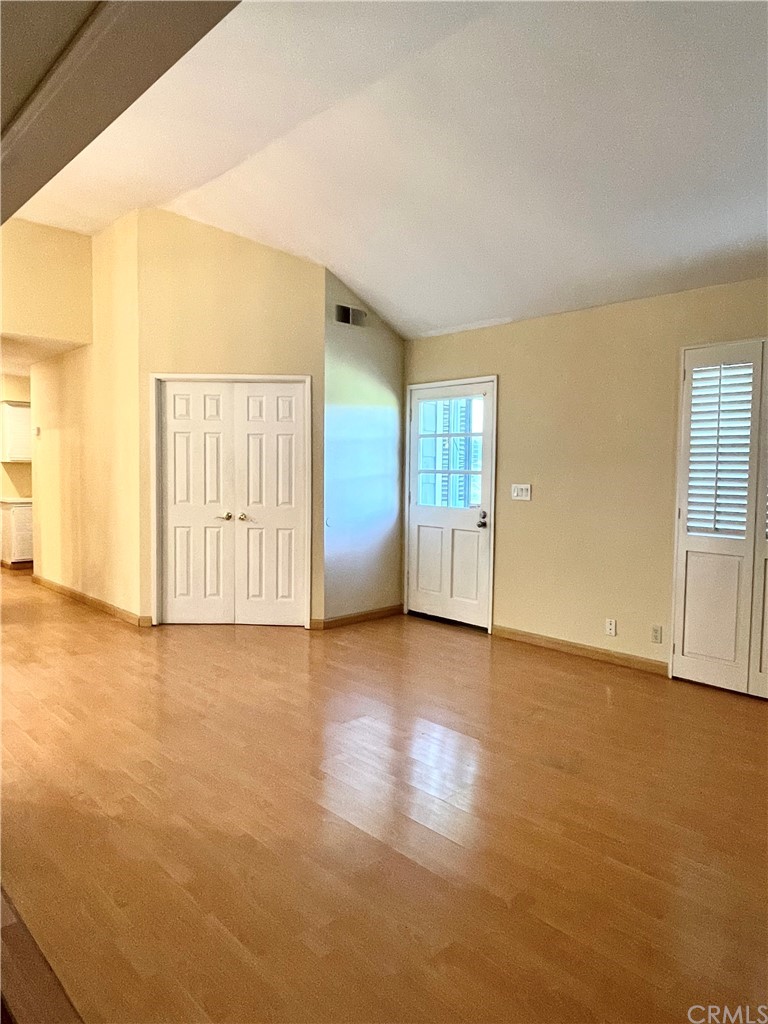 48 Riverstone, Unit 60 Irvine, CA 92606 - Photo 7 of 31 an empty room with wooden floor and windows with curtains