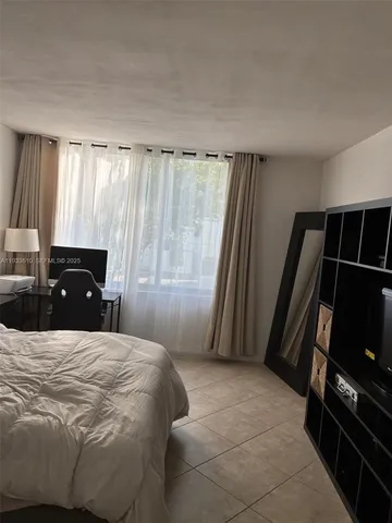 a bedroom with a bed television and a window