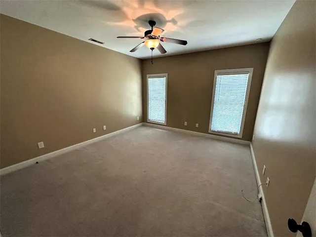 a view of an empty room with chandelier fan