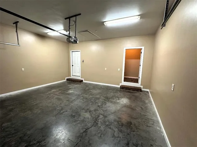 an empty room with a chandelier fan and windows