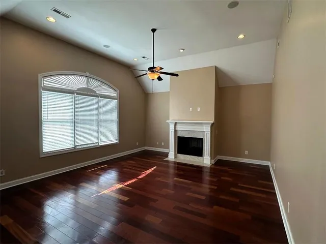 an empty room with wooden floor fireplace and windows