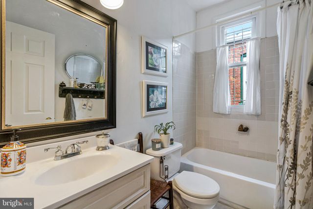 a bathroom with a sink vanity mirror bathtub and toilet