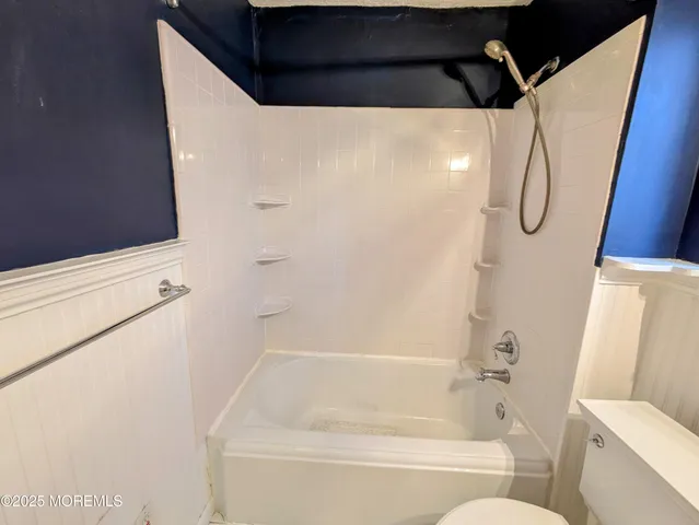 a bathroom with a shower and a white bath tub