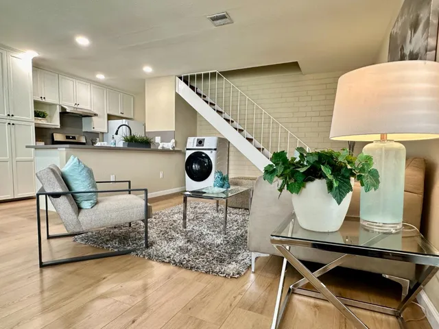 a living room with a couch and potted plant with wooden floor
