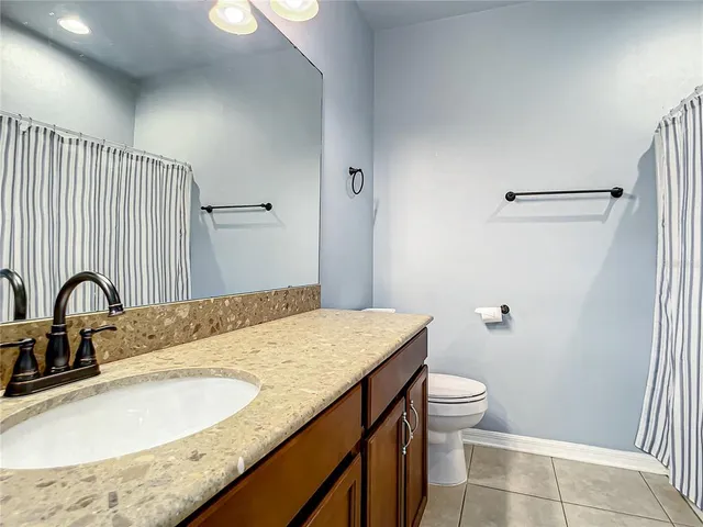 a bathroom with a granite countertop sink a toilet and a mirror