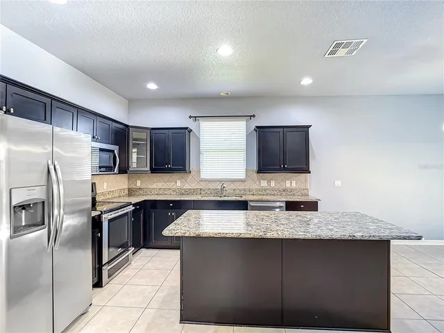 a view of kitchen with granite countertop sink and cabinets