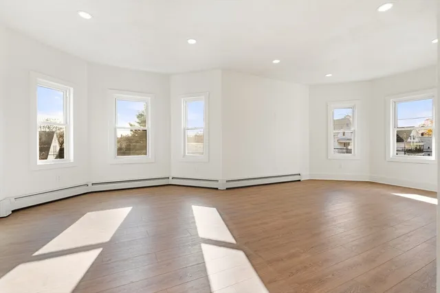 a view of an empty room with window and wooden floor