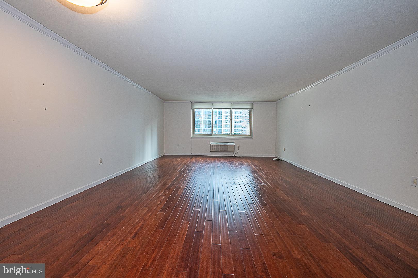 1919 Chestnut Street, Unit 1722 Philadelphia, PA 19103 - Photo 2 of 26 a view of an empty room with wooden floor and window