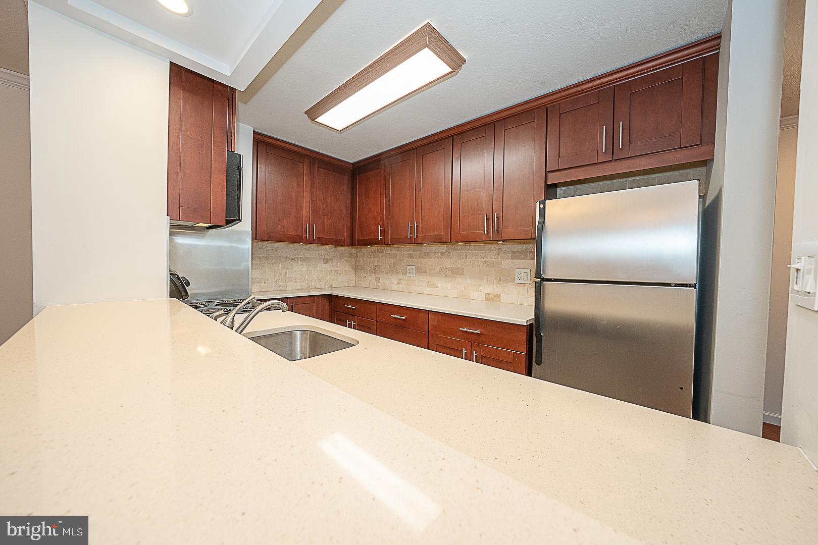 1919 Chestnut Street, Unit 1722 Philadelphia, PA 19103 - Photo 7 of 26 a kitchen with granite countertop a refrigerator and a sink