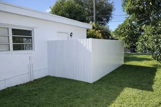 a backyard of a house with table and chairs plants and large trees