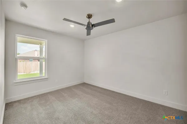 an empty room with a window and a ceiling fan