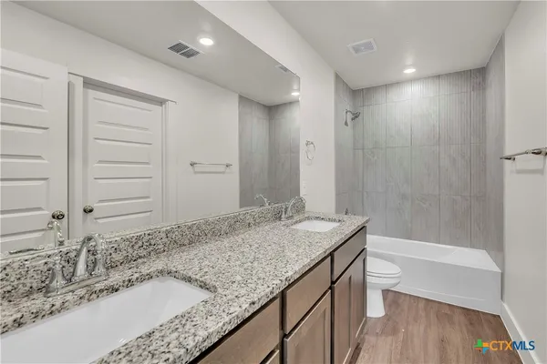 a bathroom with a granite countertop sink a toilet and bathtub