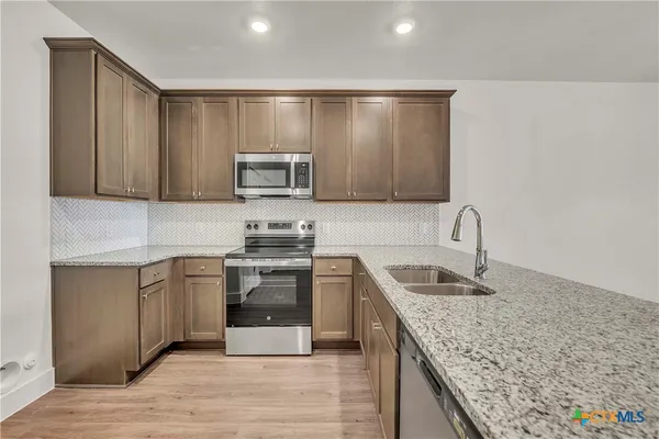 a kitchen with granite countertop a sink and steel appliances