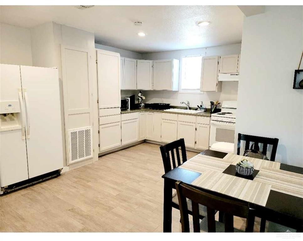 906 East Van Week Street Edinburg, TX 78541 - Photo 13 of 19 a kitchen with a table chairs stove and white cabinets