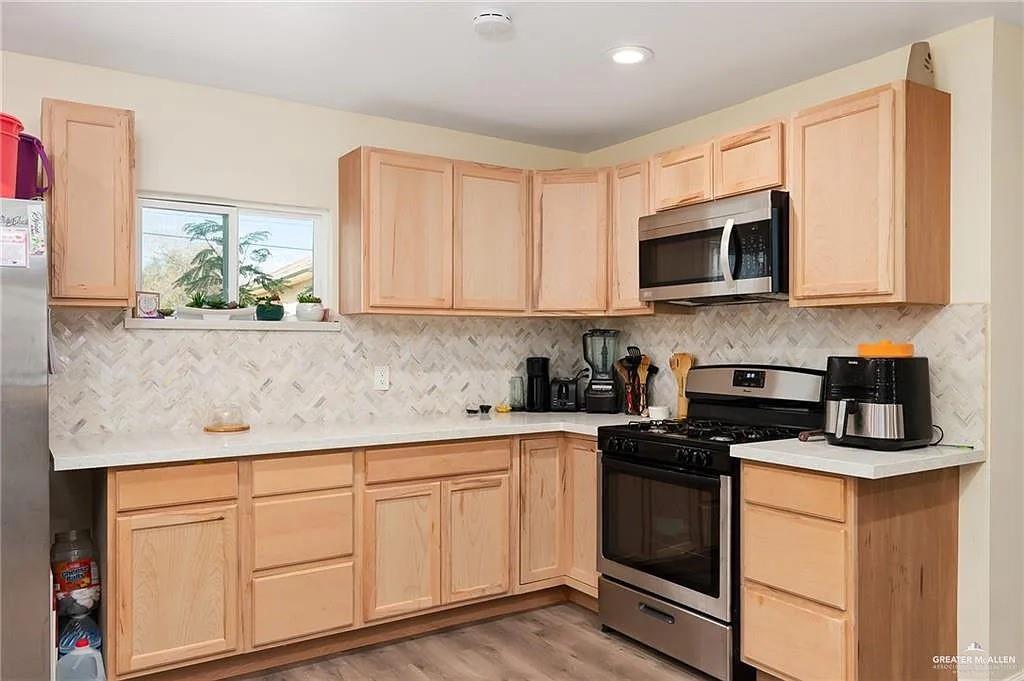906 East Van Week Street Edinburg, TX 78541 - Photo 16 of 19 a kitchen with granite countertop white cabinets sink and stainless steel appliances