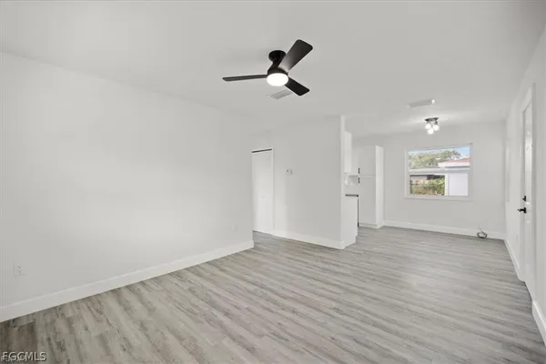 a view of empty room with wooden floor and ceiling fan