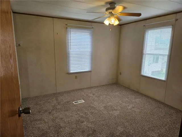 a view of an empty room with window chandelier fan