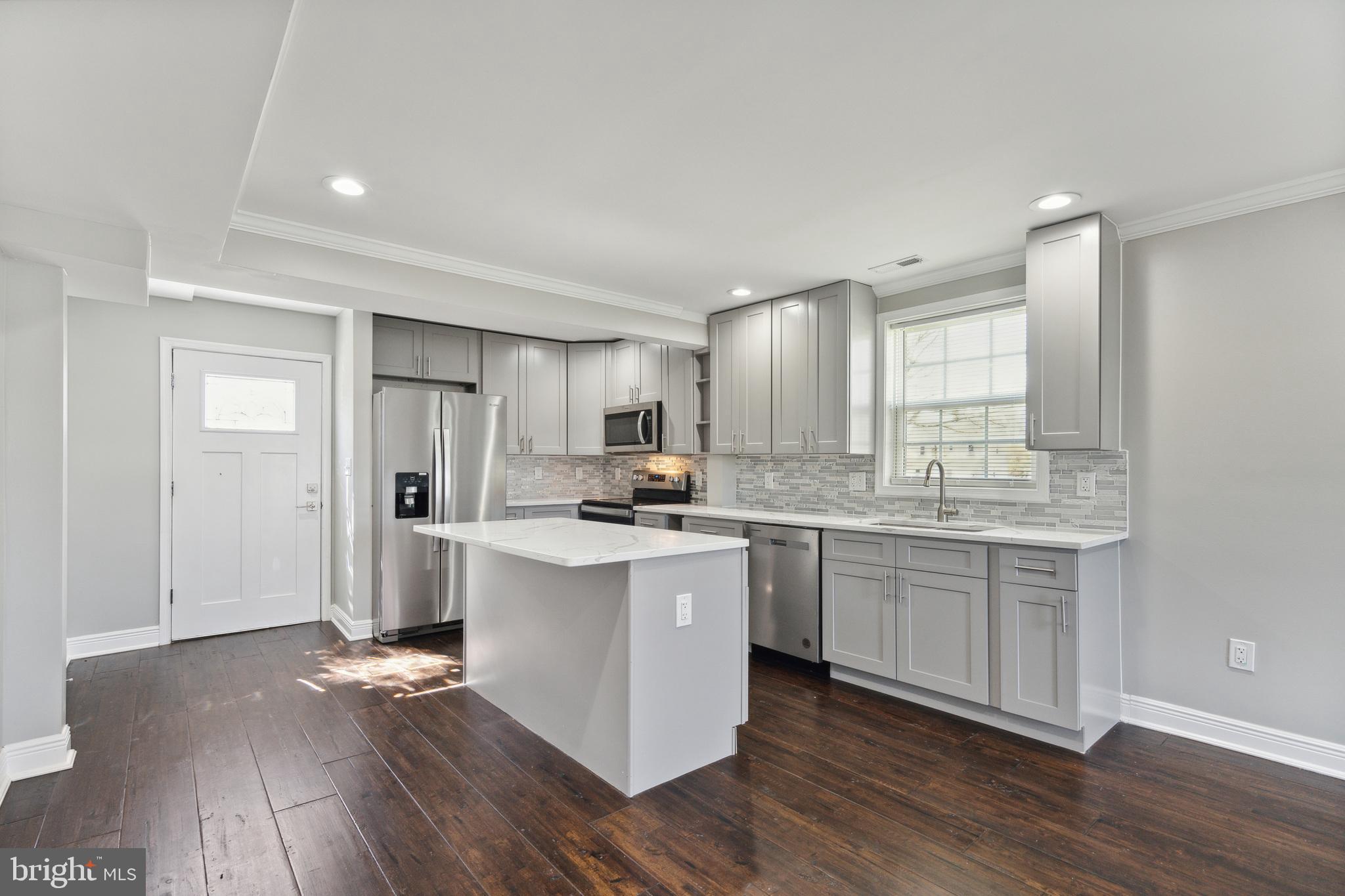 a kitchen with kitchen island granite countertop a sink cabinets and wooden floor