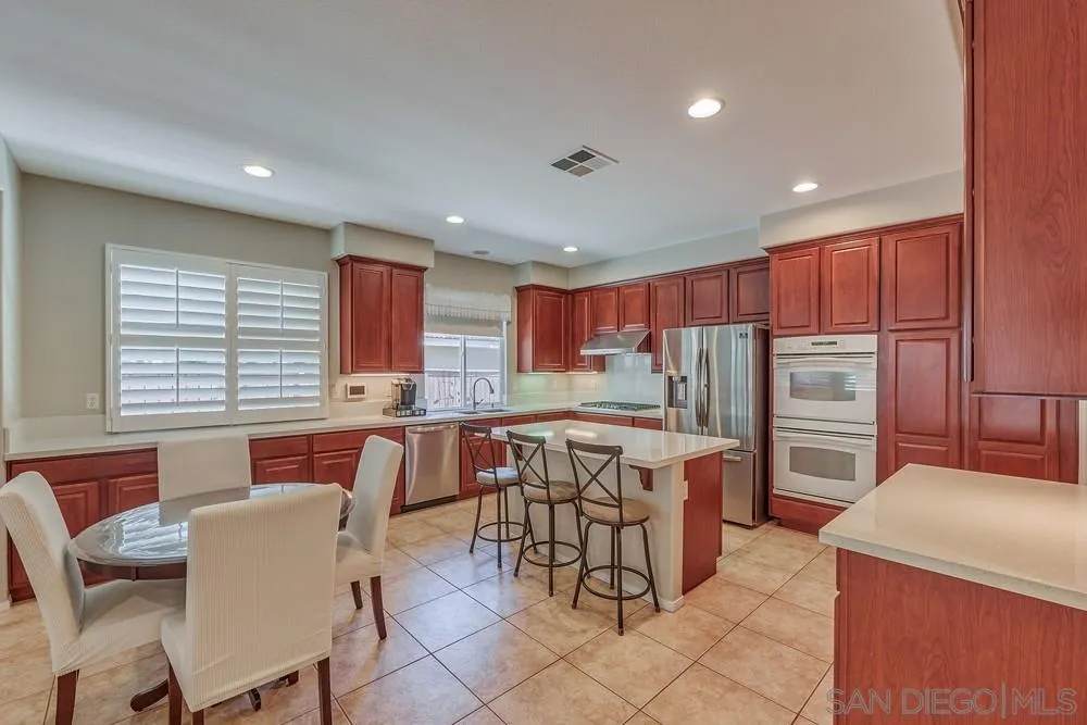 32758 Stonefield Lane Temecula, CA 92592 - Photo 4 of 30 a kitchen with stainless steel appliances kitchen island granite countertop a table chairs and a refrigerator