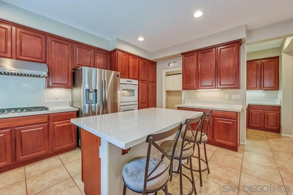 32758 Stonefield Lane Temecula, CA 92592 - Photo 5 of 30 a kitchen with stainless steel appliances granite countertop a table chairs sink refrigerator and cabinets