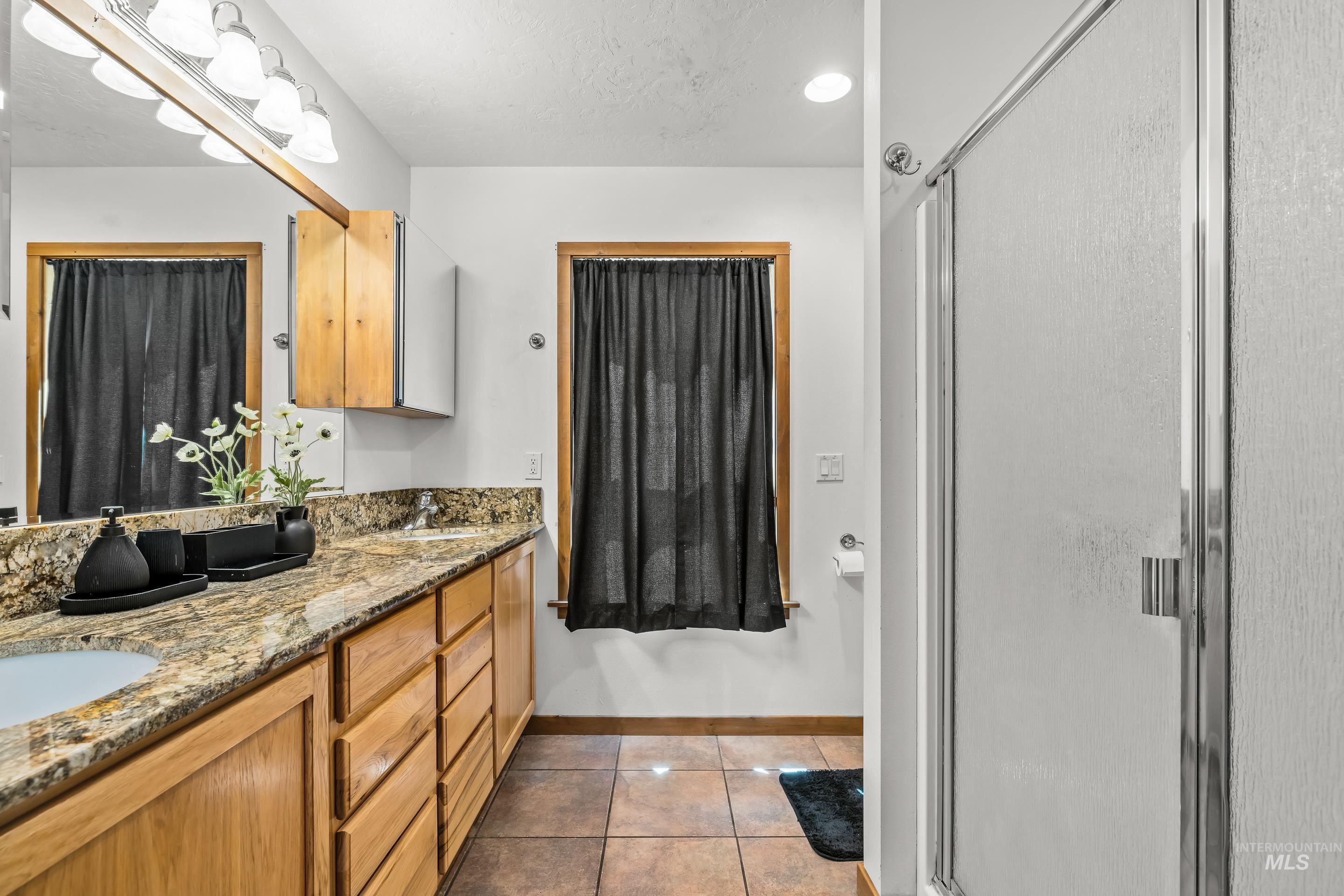 92 Cruickshank Road Horseshoe Bend, ID 83629 - Photo 24 of 50 Bathroom featuring a double vanity with stone countertops, wood-finish cabinetry, and a mirrored wall