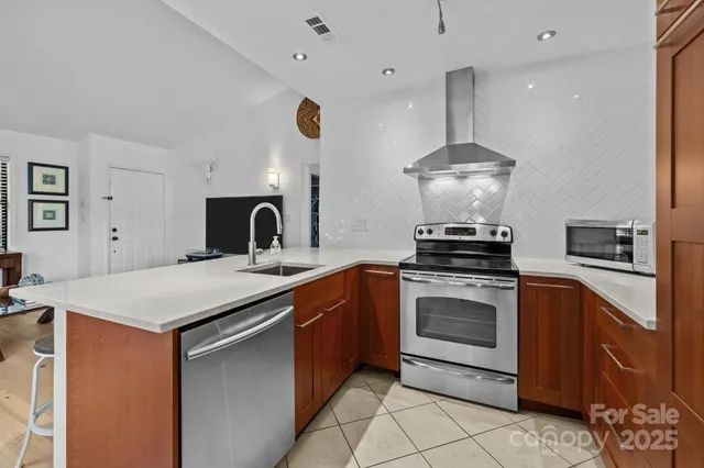 a kitchen with stainless steel appliances granite countertop a sink a stove and a refrigerator
