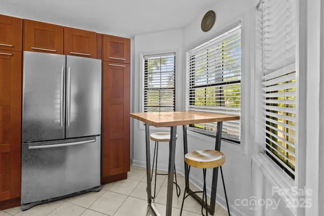 a kitchen with stainless steel appliances a refrigerator a table and chairs in it
