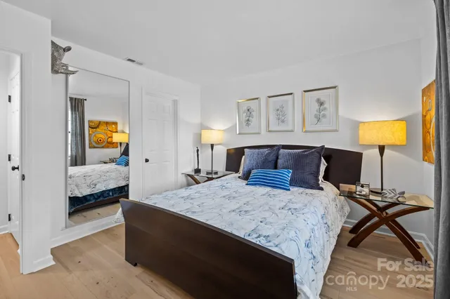a bedroom with a bed and a potted plant on the dresser