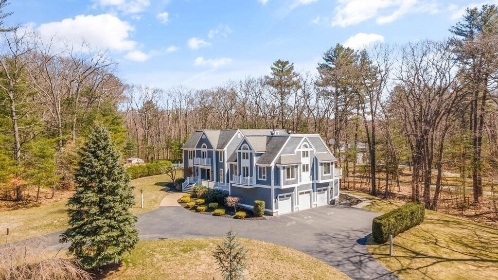 a view of a big house with large trees and cars parked
