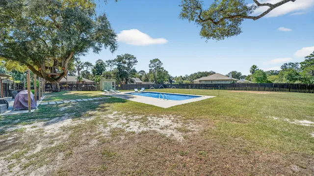 a view of a patio with table and chairs potted plants and large tree