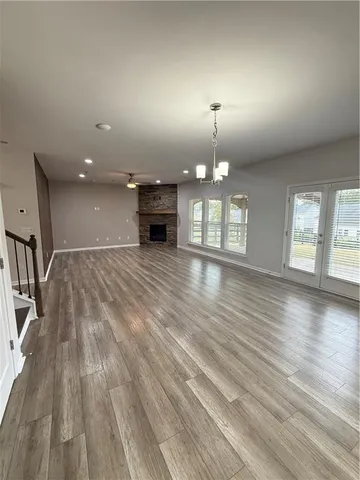 an empty room with wooden floor chandelier and windows