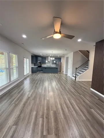a view of empty room with wooden floor and fan