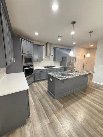 a large kitchen with kitchen island a sink a stove a oven a counter space and cabinets