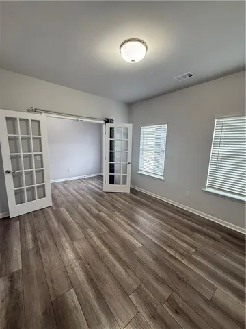 a view of an empty room with a window and wooden floor