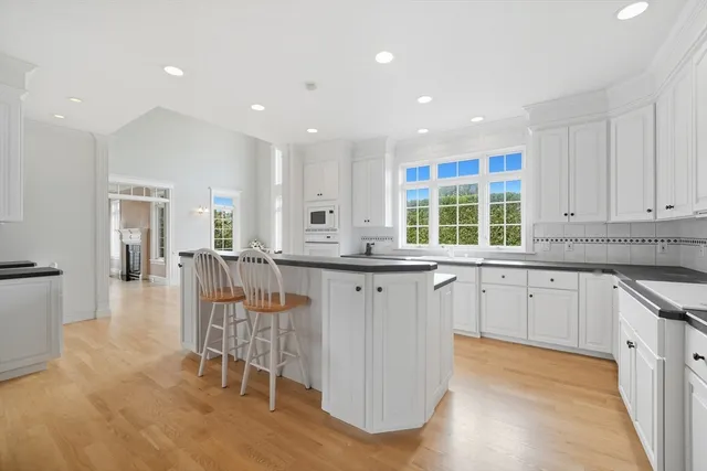 a kitchen with stainless steel appliances granite countertop a stove a sink a oven with white cabinets and wooden floor