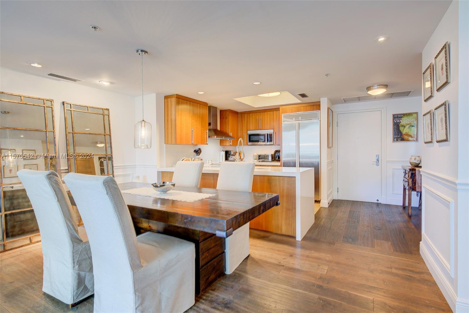 a kitchen with stainless steel appliances granite countertop a table chairs sink refrigerator and cabinets