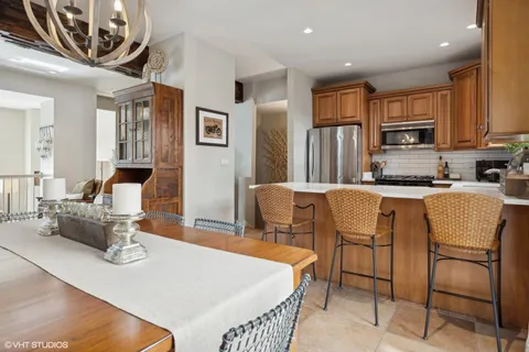 a kitchen with stainless steel appliances granite countertop a table chairs and a refrigerator
