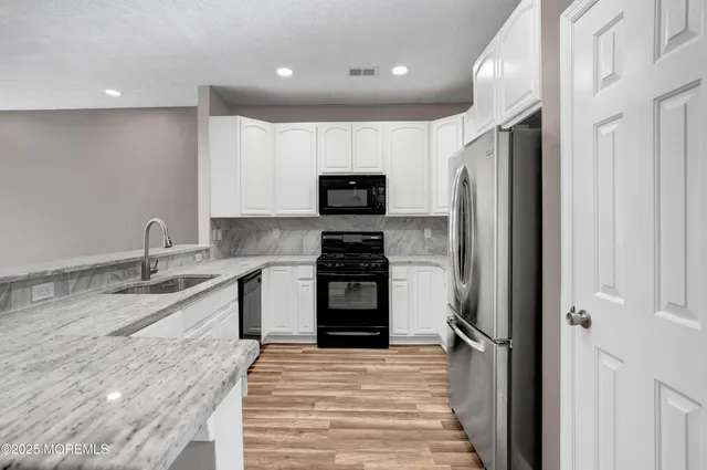 a kitchen with granite countertop a refrigerator and a stove top oven