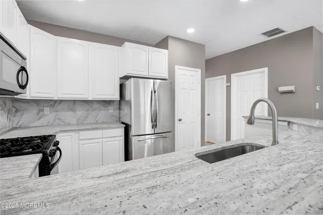 a kitchen with stainless steel appliances kitchen island a refrigerator sink and cabinets