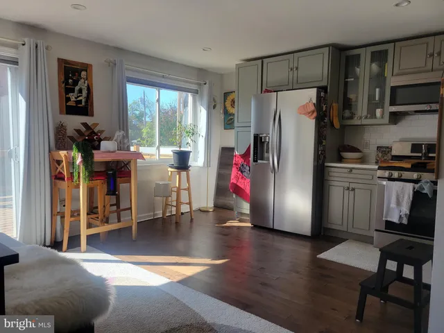 a kitchen with stainless steel appliances a refrigerator a stove a dining table and chairs with wooden floor